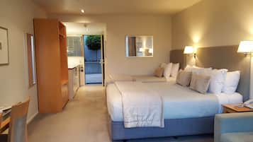 A hotel room with a large bed, bedside tables, a wardrobe, and a view into the kitchen area.