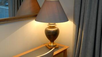 Uma luminária em uma mesa de cabeceira com um espelho acima.
