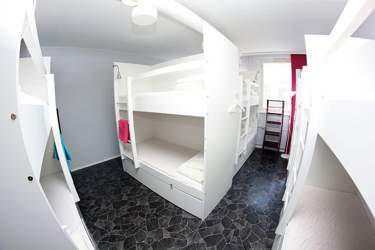 A bunk bed room with a curved ceiling and a small window.