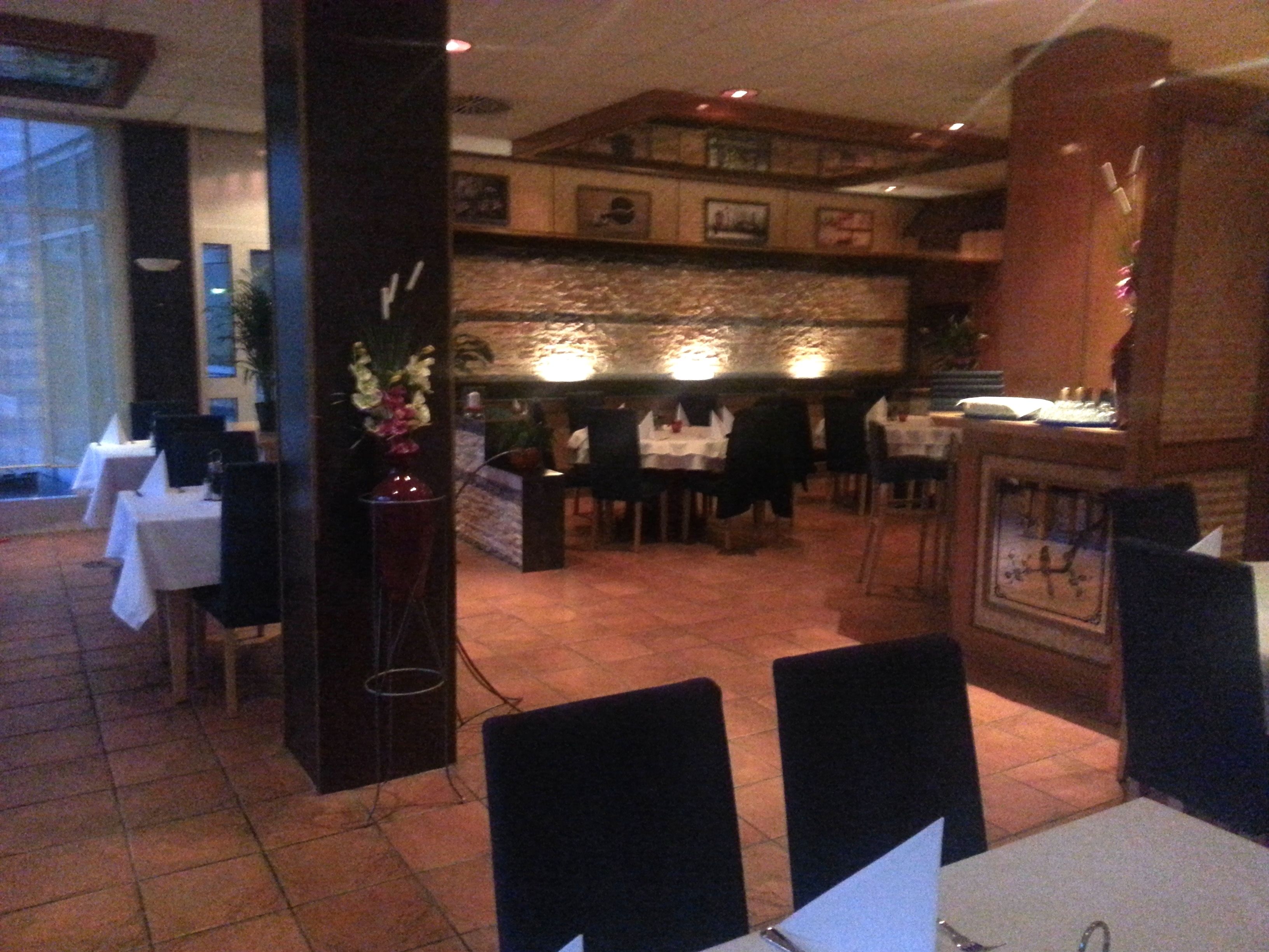 A restaurant with tables and chairs, a decorative vase, and a clock on the wall.