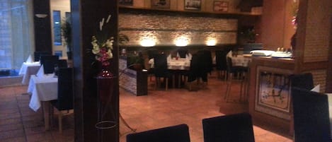 Un restaurante con mesas y sillas, un jarrón decorativo y un reloj en la pared.