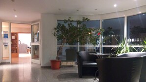 A lobby with a reception desk, seating area, and large windows. - Central Hotel (Winnenden)