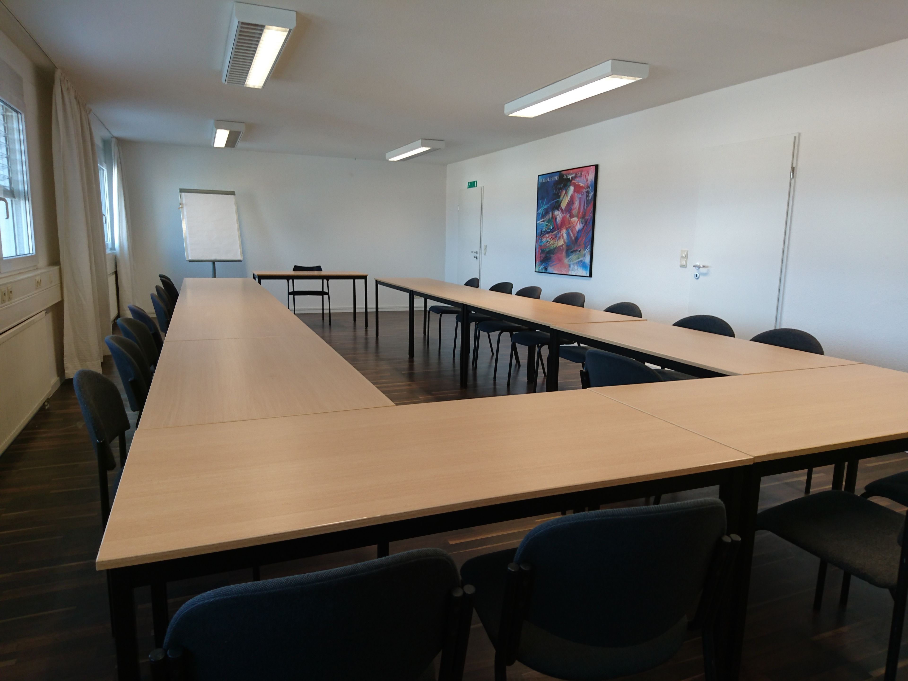 A conference room with a long table, chairs, a whiteboard, and a colorful abstract painting on the wall.