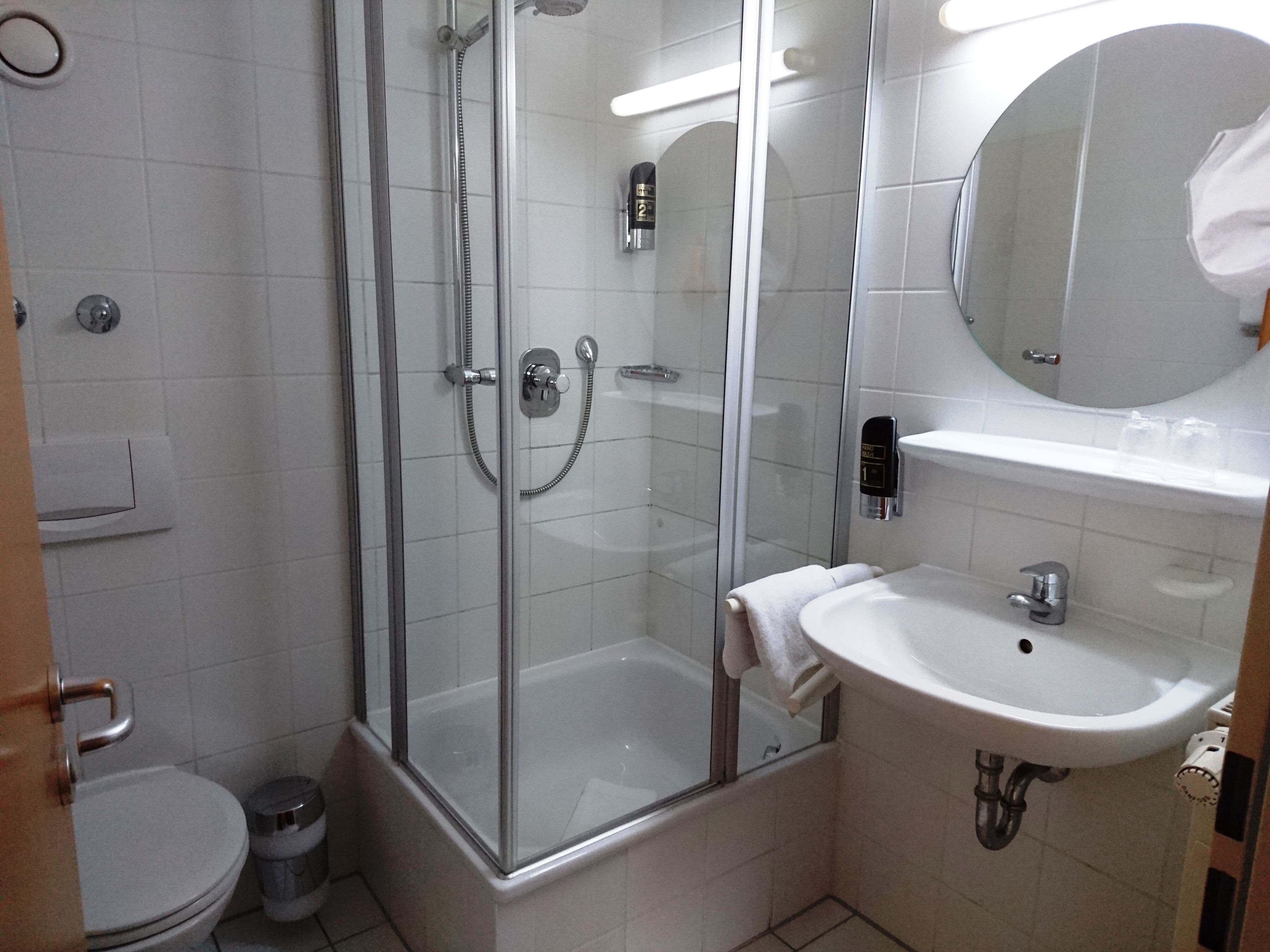 A modern bathroom with a glass-enclosed shower, a white sink, and a toilet.