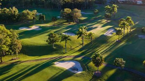 Ilmakuva golfkentästä, jossa on hiekkabunkkereita, palmuja ja kauempana näkyy klubitalo.