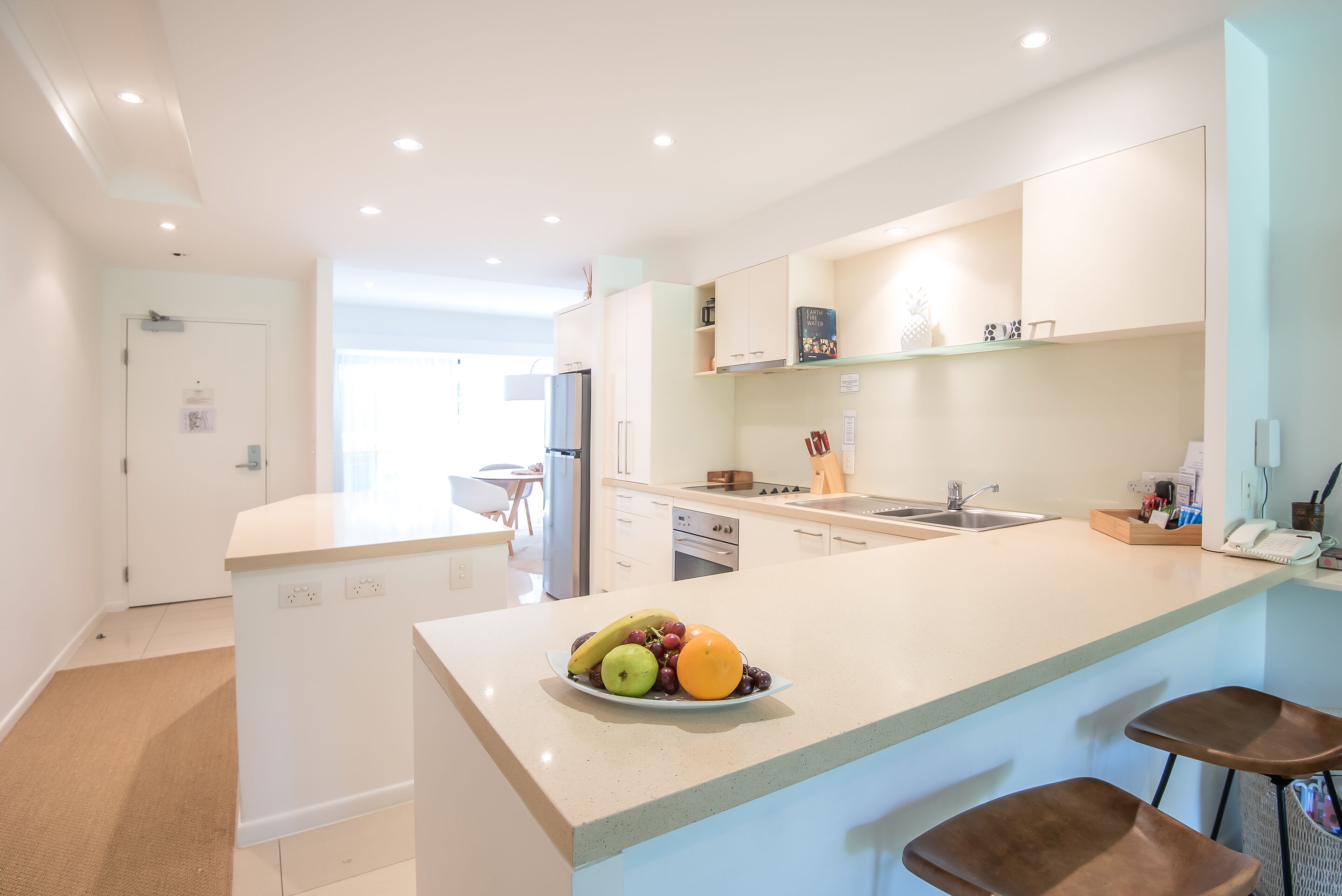 A modern kitchen with a central island, a dining area, and a view to the living room.