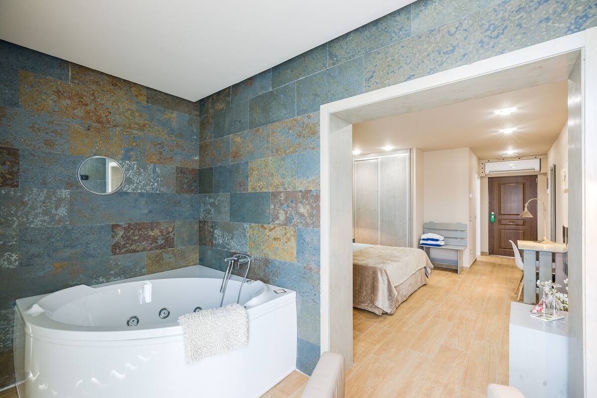 A modern bathroom with a freestanding bathtub, a mirror, and a shower area.
