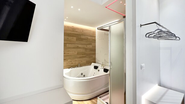 Un baño moderno con una bañera independiente, un espejo y un perchero de pared.