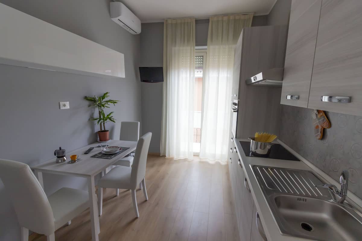 A modern kitchen with a white countertop, a sink, and a dining area with a table and chairs.