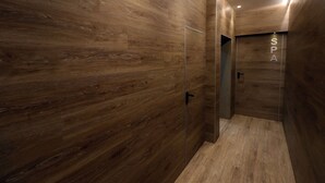 Un spa moderno con paredes de madera y una puerta de vidrio que da a una zona de ducha.