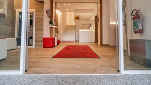Un moderno vestíbulo de hotel con alfombra roja, piso de madera y un mostrador de recepción.