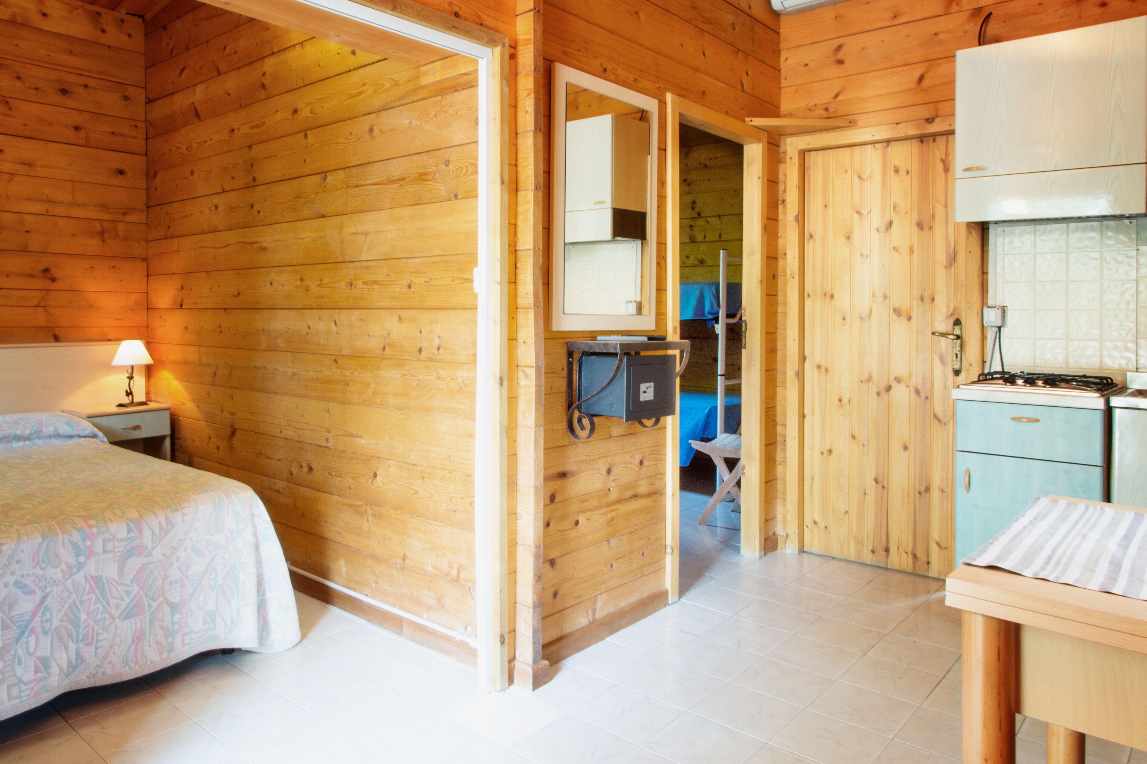 A wooden cabin with a bed, a desk, and a kitchenette.