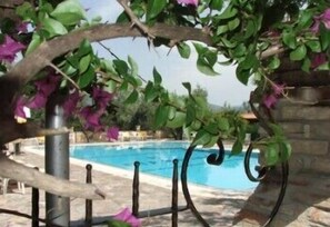 A swimming pool with a stone wall and a metal fence. - Albergo Il Giardino (Ischitella)