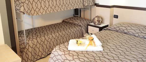 Una habitación de hotel con literas, una mesita de noche con un adorno y una cama bien hecha.