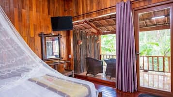 Quarto de madeira com uma cama, televisão e vista para o exterior.