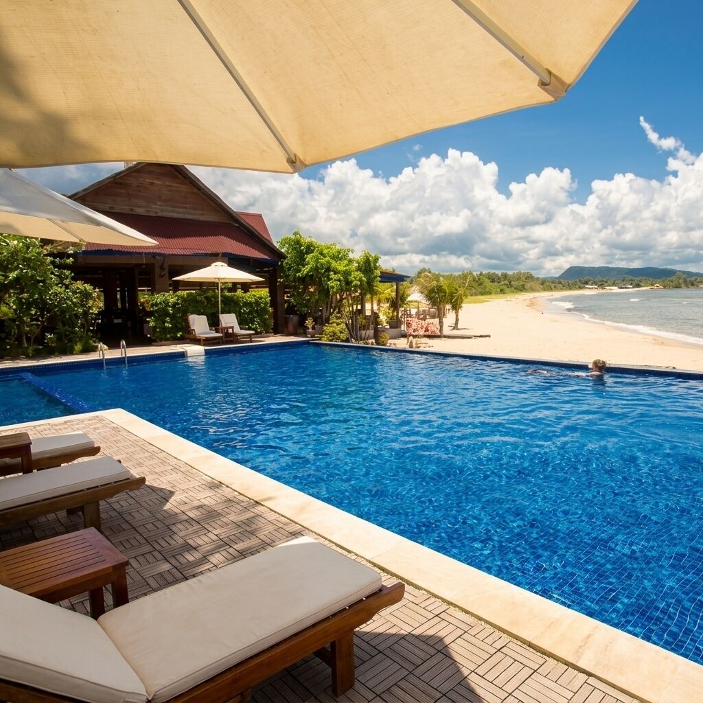 Piscina com espreguiçadeiras e guarda-sóis, vista para a praia e área coberta com cadeiras.