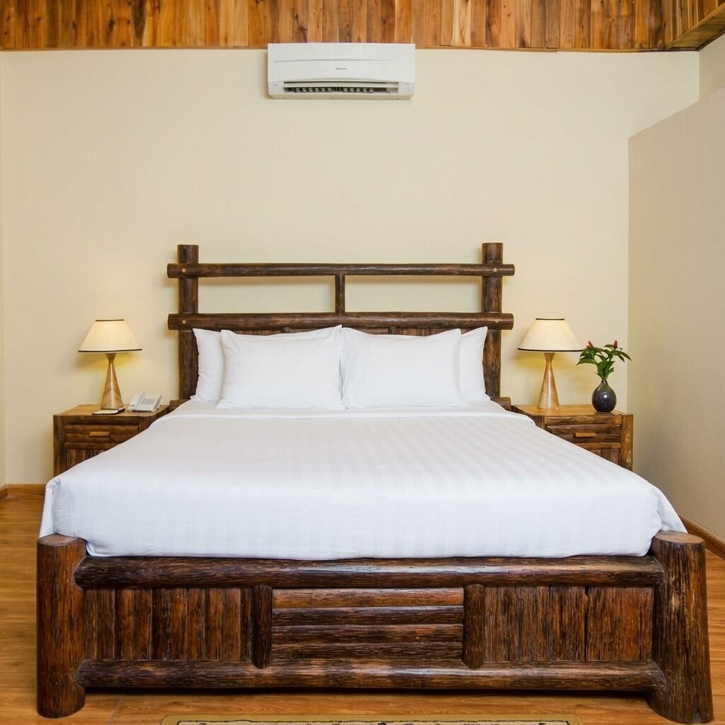 A bed with a wooden headboard, white bedding, and two bedside tables with lamps and a vase.