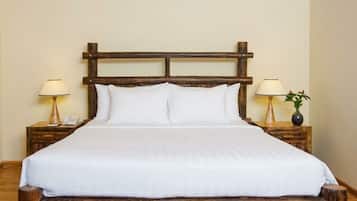 A bed with a wooden headboard, white bedding, and two bedside tables with lamps and a vase.