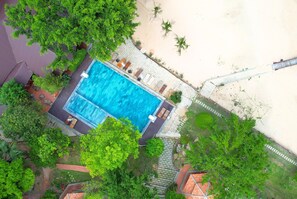 An aerial view of a swimming pool surrounded by lush greenery and a sandy beach area. - Milana Beach Resort & Spa Phu Quoc (Phu Quoc)