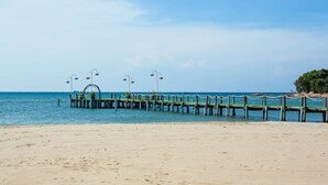 A beach with a wooden pier extending into the sea, featuring a seating area with tables and chairs. - Milana Beach Resort & Spa Phu Quoc (Phu Quoc)