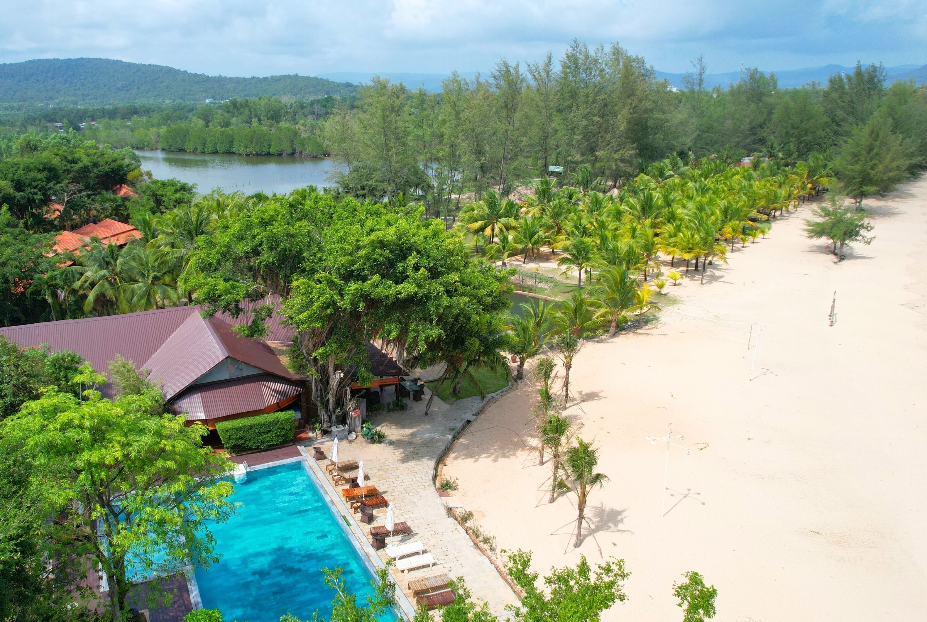 Un complexe hôtelier doté d’une piscine, d’une plage et d’une végétation luxuriante.