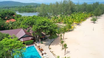 Un complexe hôtelier doté d’une piscine, d’une plage et d’une végétation luxuriante.