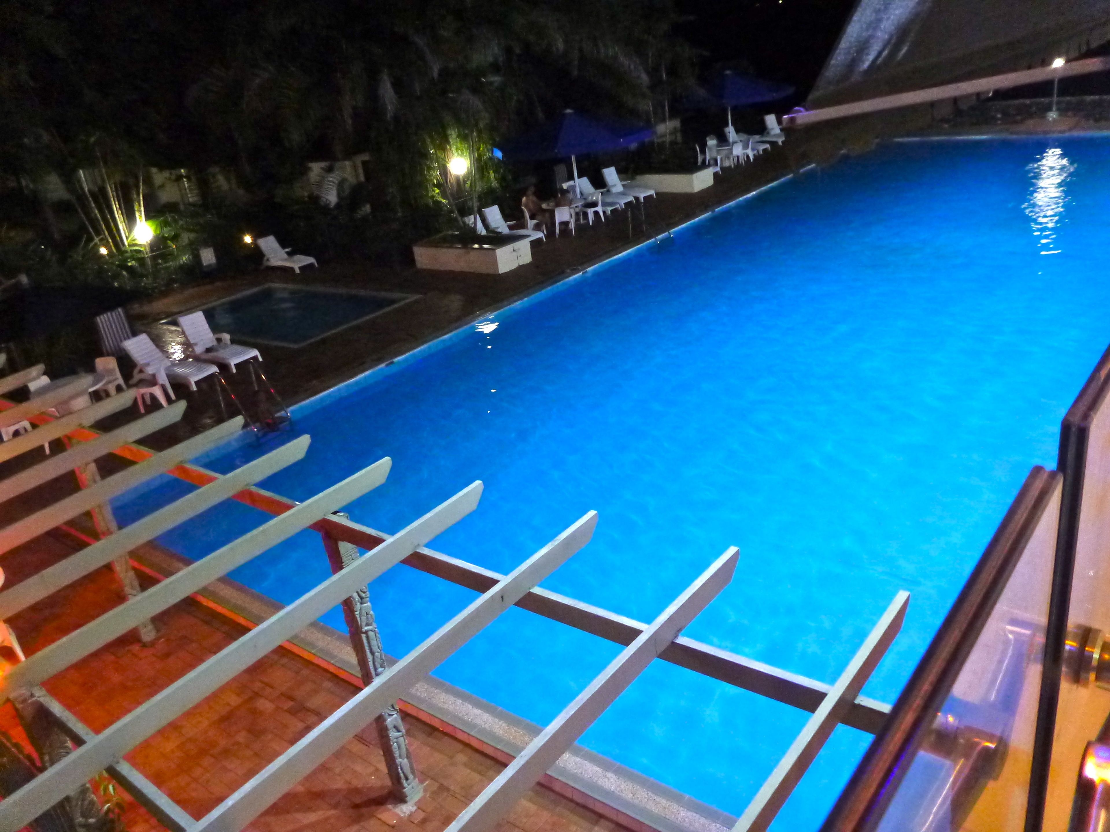 Een buitenzwembad, parasols bij het zwembad en ligstoelen