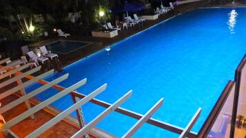 Een buitenzwembad, parasols bij het zwembad en ligstoelen