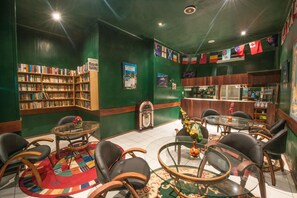 A library with bookshelves, a jukebox, and a bar area with chairs and tables. - Madang Resort (Madang)