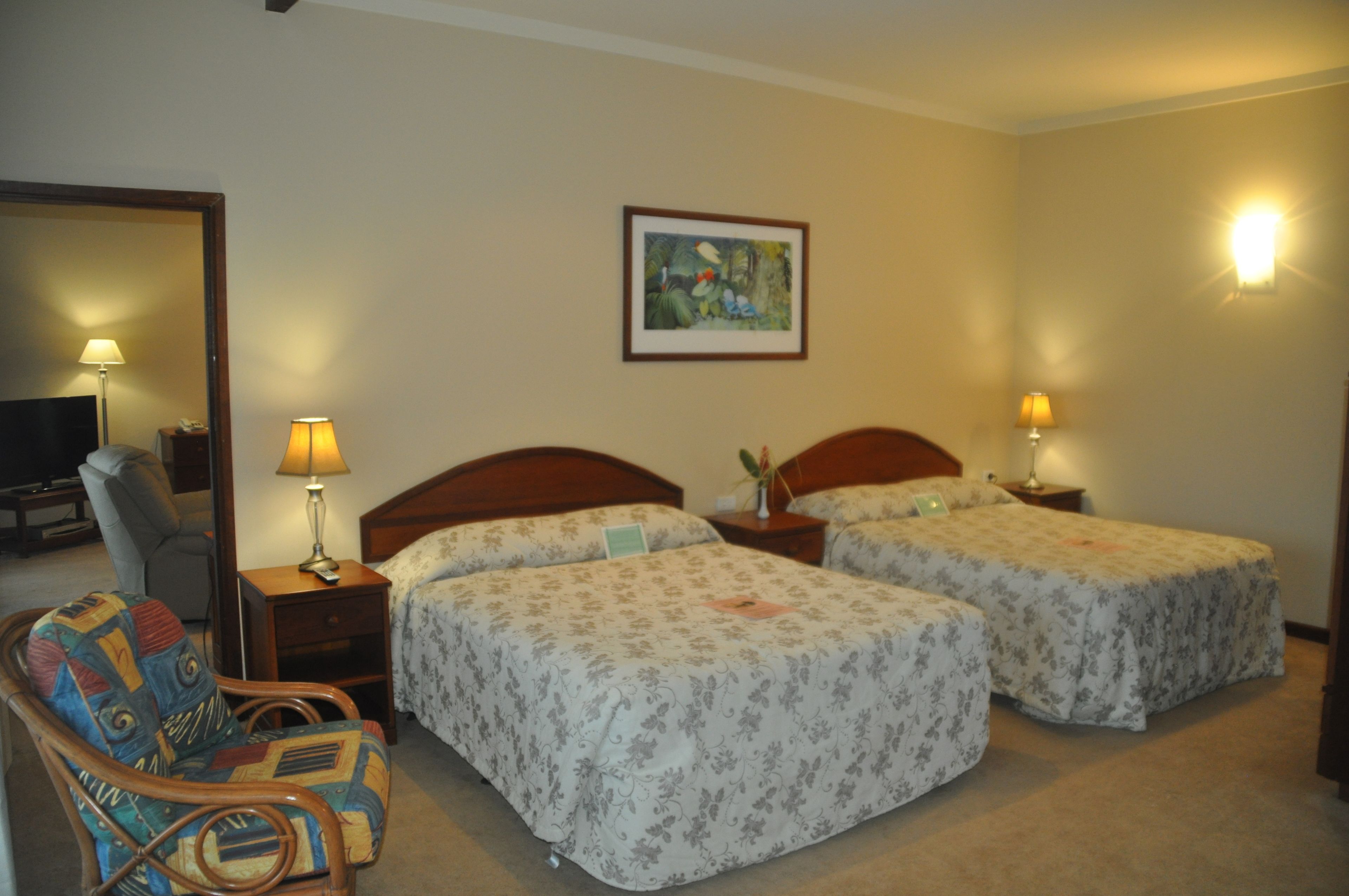 Een hotelkamer met twee bedden, een stoel, een bureau en een schilderij aan de muur.