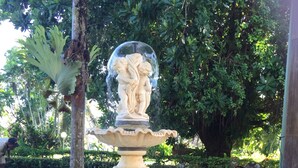 Una fontana con una statua, circondata da rocce e vegetazione.
