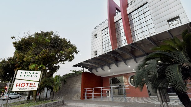 A Costa Linda Hotel with a modern design, featuring a prominent 'M' structure, a covered entrance, and a sign indicating hotel parking.