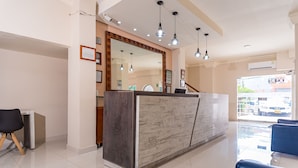 A reception area with a marble counter, blue chairs, and pendant lighting.