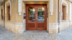A building entrance with a wooden double door, a tiled pavement, and a sign above the door. - Alda Ciudad de Toro (Toro)