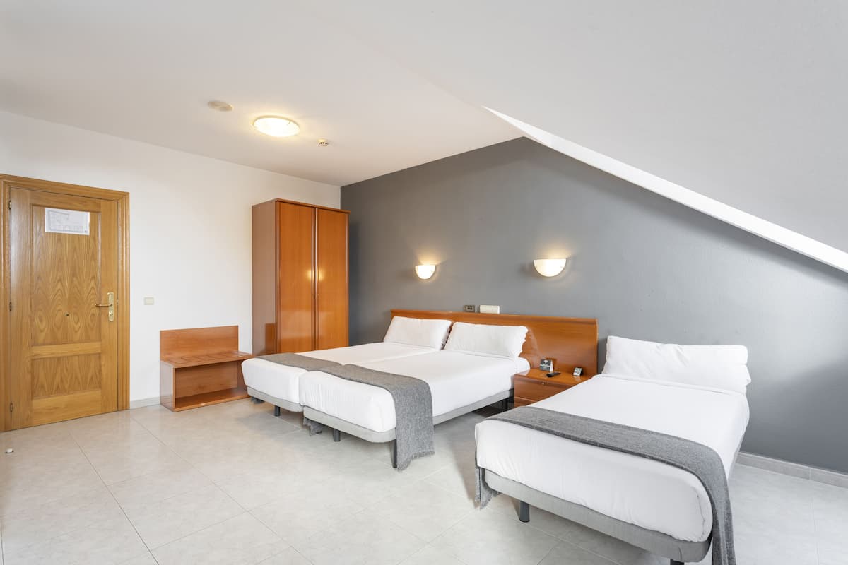 A bedroom with two beds, a wooden wardrobe, and a bench.
