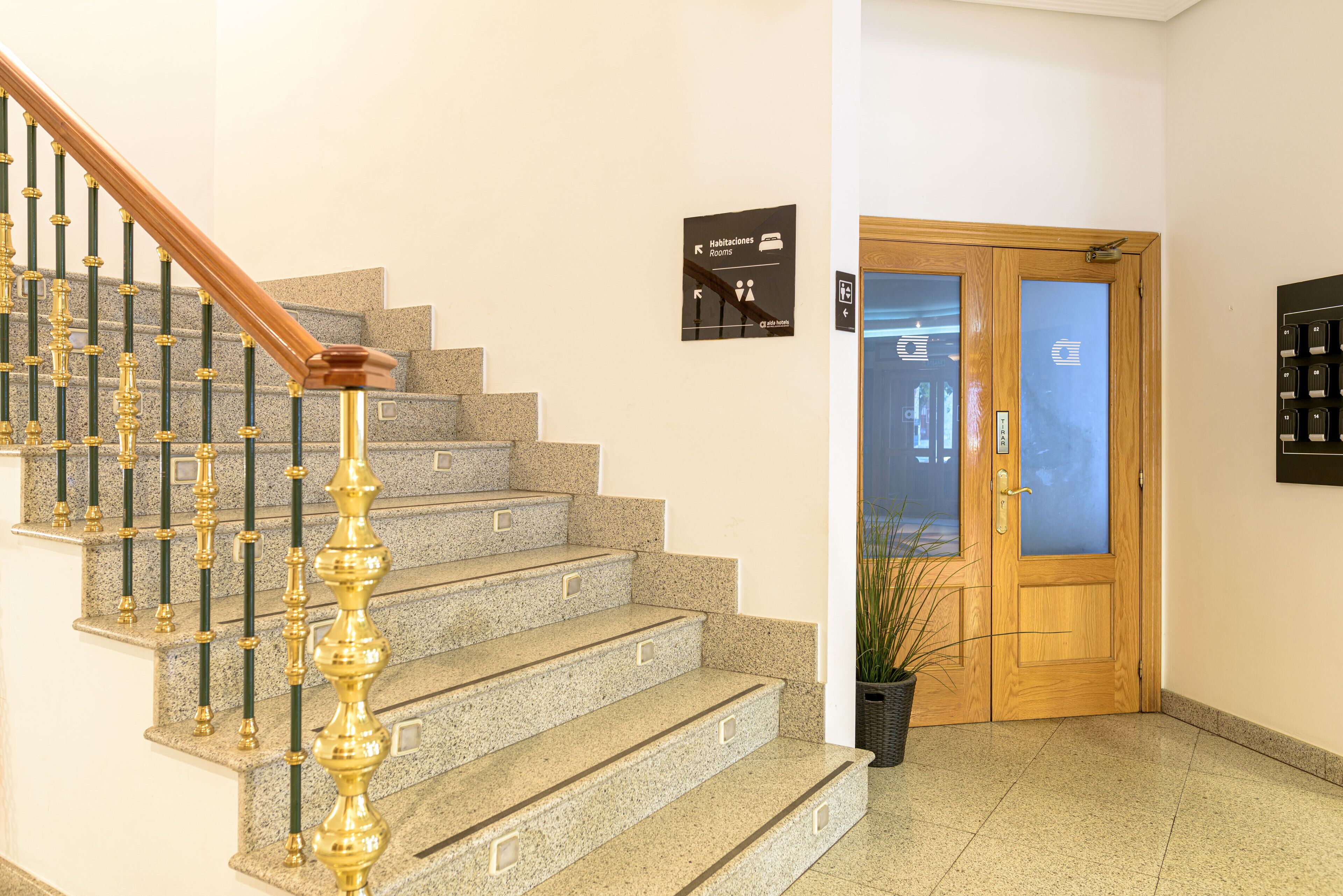 A staircase with a wooden handrail and stone steps leading to a door with a frosted glass panel.