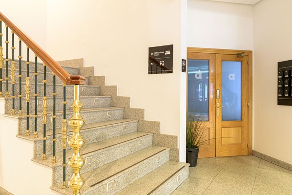 Una escalera de piedra con barandilla de madera que conduce a una puerta con panel de vidrio esmerilado.