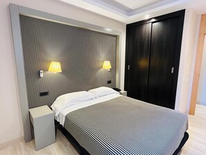 Un dormitorio moderno con cama, mesitas de noche, armario y lámparas de pared.