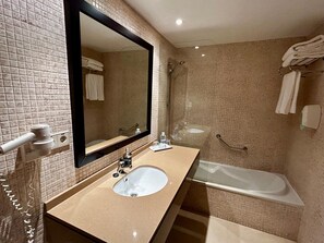 Un baño con un espejo grande, un lavamanos, una bañera y una ducha.