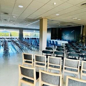 Konferenssihuone, jossa on riveissä tuoleja, pitkä pöytä ja suuret ikkunat.