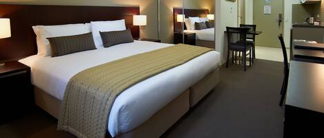 Una habitación de hotel con una cama grande, mesitas de noche, un escritorio y una silla.