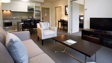 A modern living room with a sofa, armchair, coffee table, and a flat-screen TV.