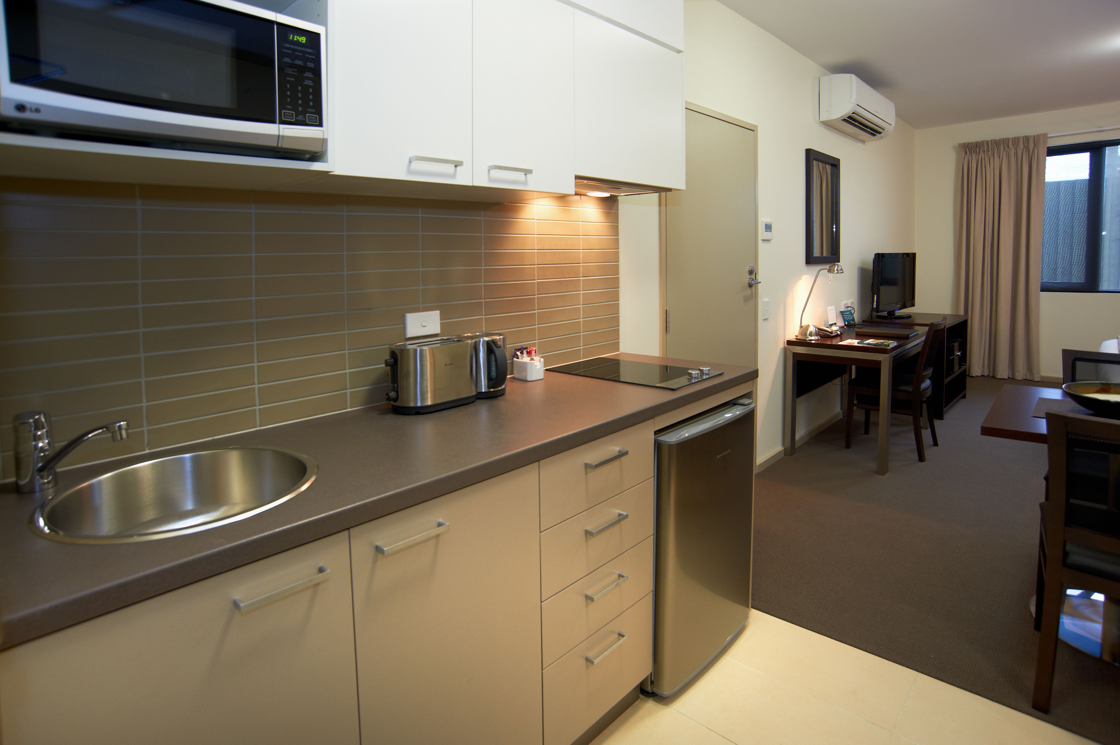 Cocina compacta con microondas, fregadero y lavavajillas. Cuenta con una zona de comedor con mesa y sillas.