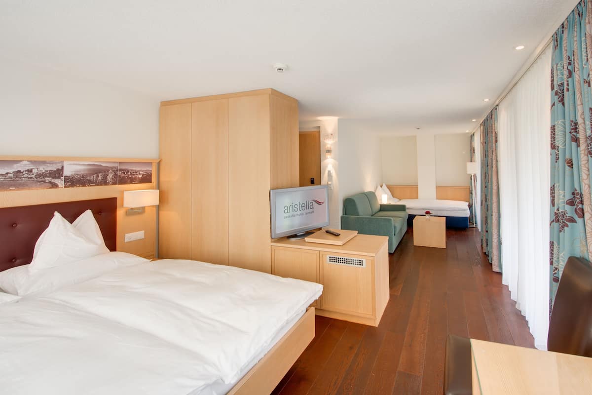 Una habitación de hotel con cama, escritorio, televisor y sofá.