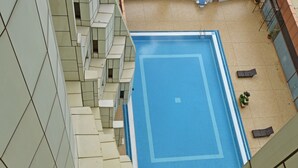 Una piscina en la azotea con un borde de baldosas, rodeada por un edificio de diseño geométrico.