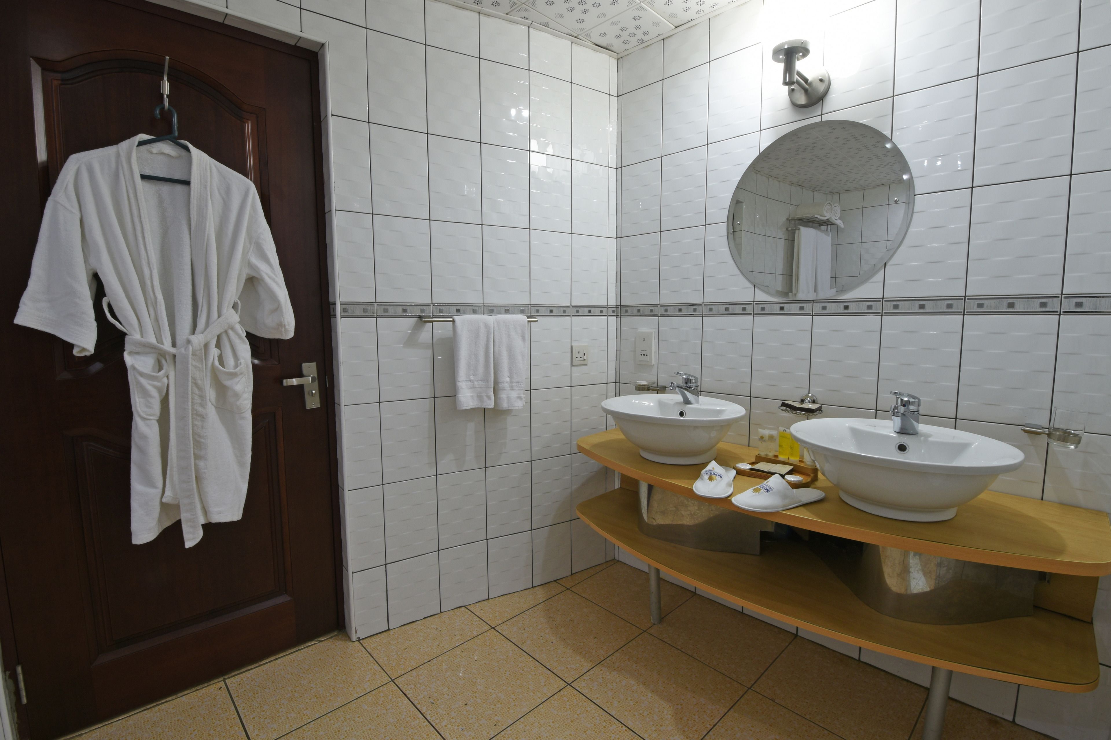 A bathroom with two sinks, a mirror, and a robe hanging on a door.