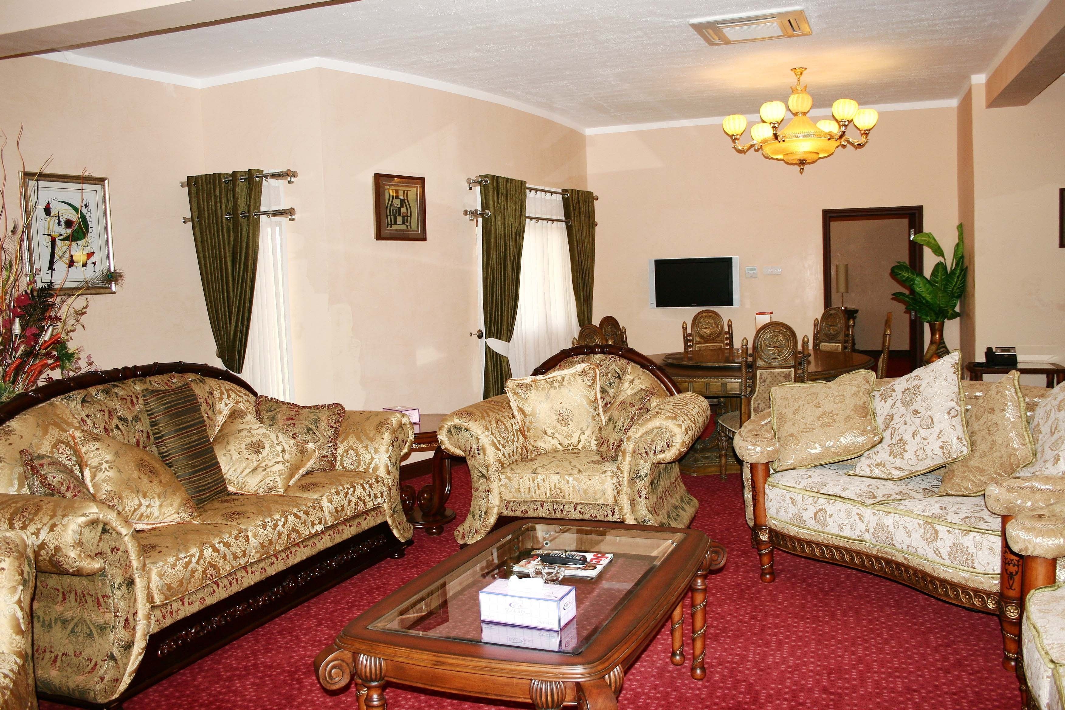 A traditional living room with two ornate sofas, a coffee table, and a chandelier.