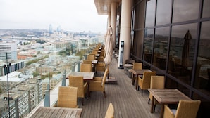 A rooftop terrace with wicker furniture and a city view. - The Landmark Hotel (Baku)