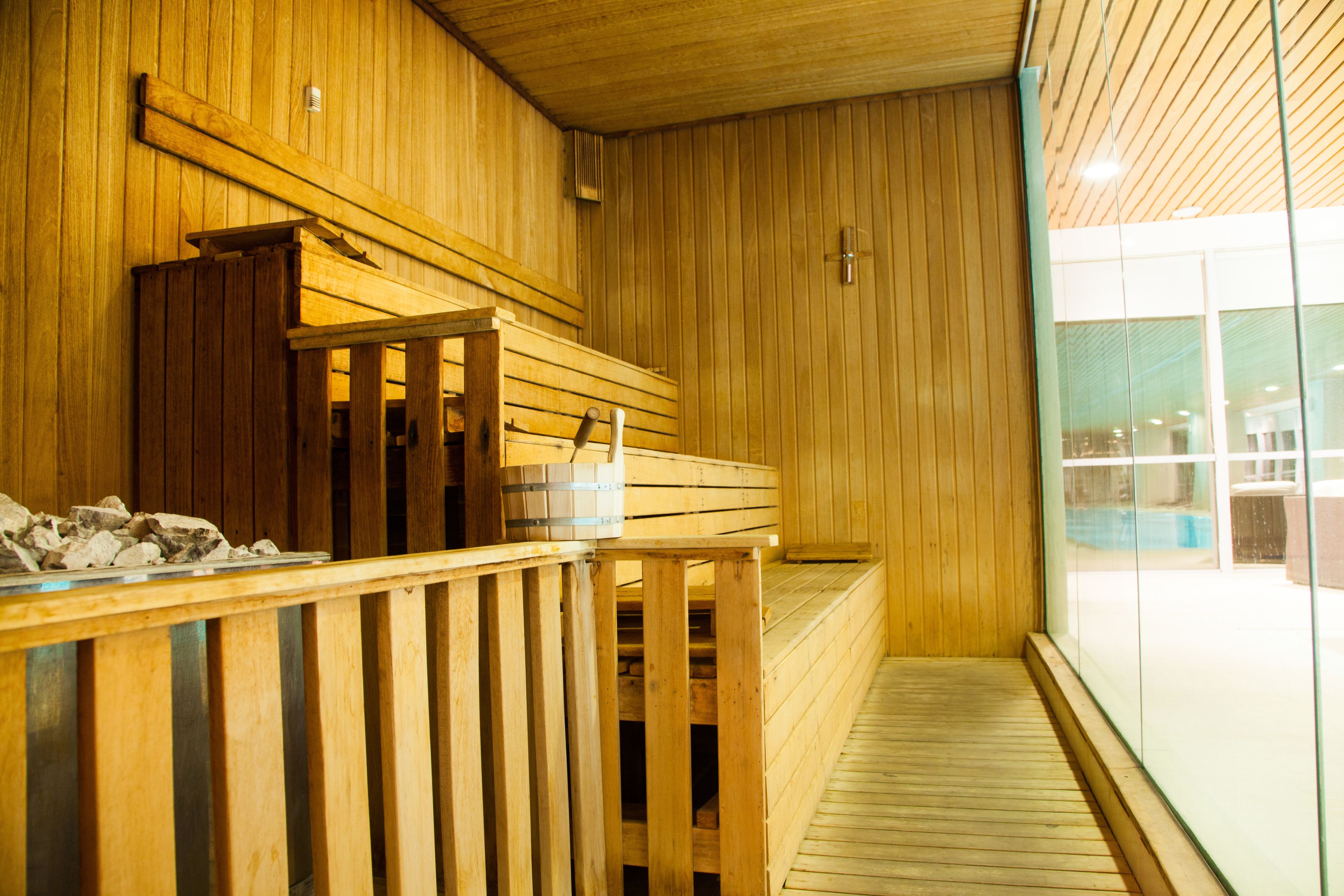 A wooden sauna with benches and a wooden railing.
