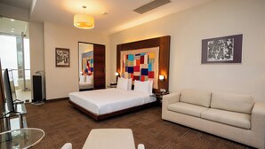 A hotel room with a bed, a sofa, a glass table, and a TV. - The Landmark Hotel (Baku)